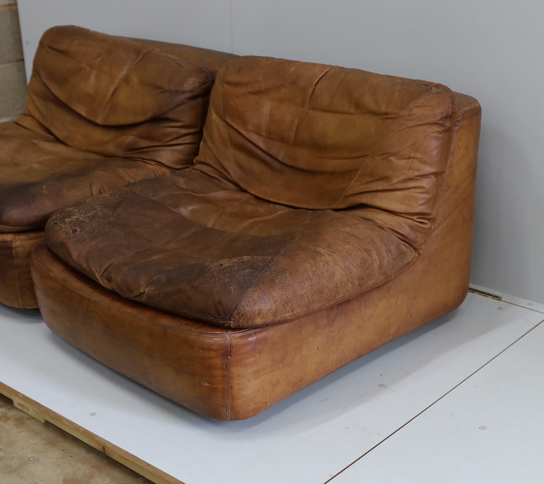 A pair of German Dreipunkt tan leather easy chairs, width 86cm, depth 96cm, height 60cm